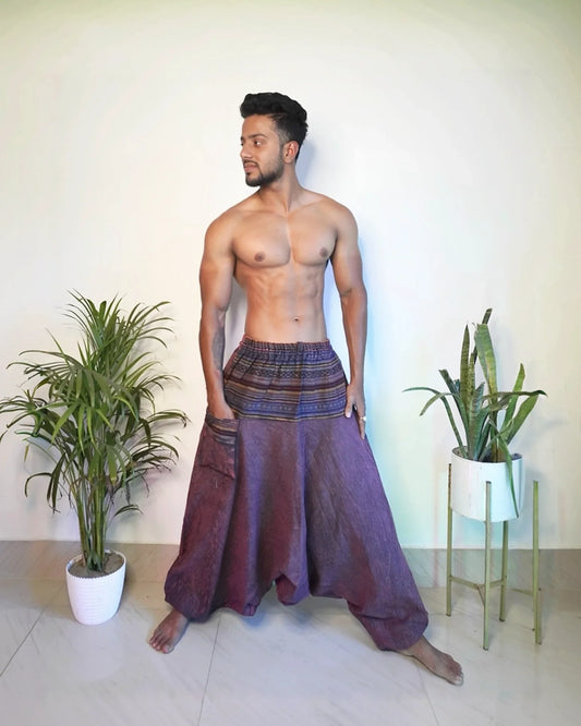 Man wearing a harem pants standing in a room with plants.