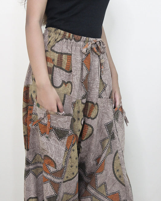 Person wearing a patterned harem pant with a plain background