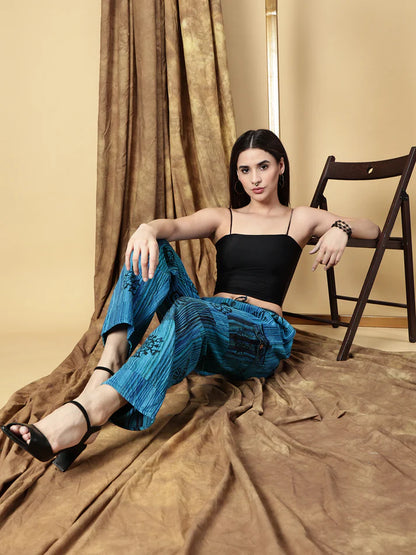 Woman sitting on a chair wearing a black top and blue pants in a room with brown curtains.