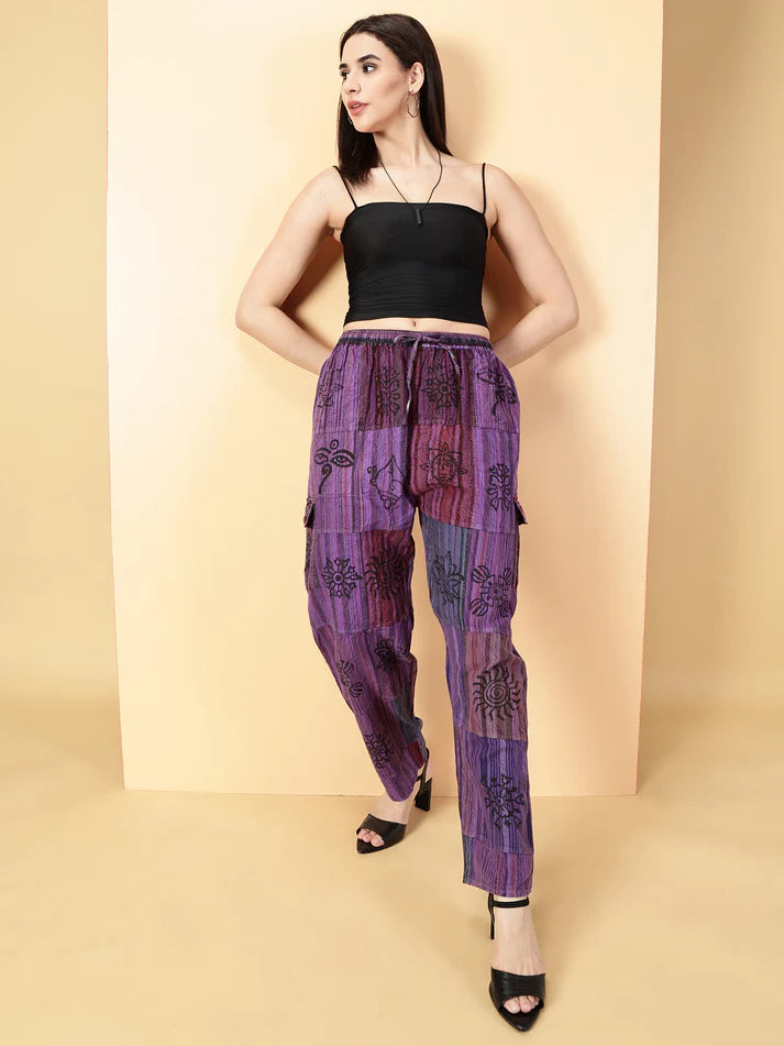 Woman wearing a black top and purple patterned pants on a beige background