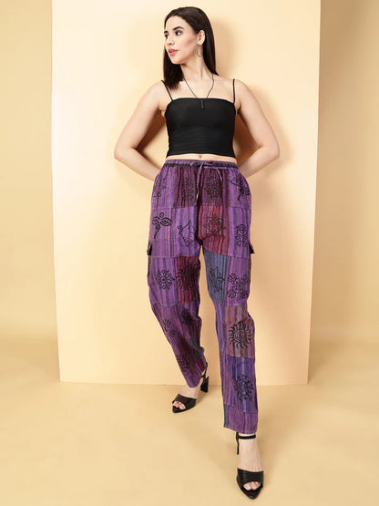 Woman wearing a black top and purple patterned pants on a beige background