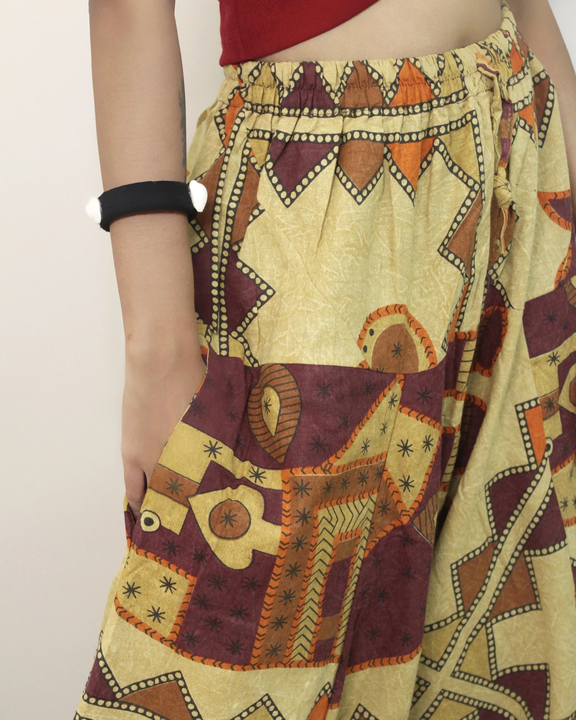 Traditional patterned fabric of harem pants draped over a person against a plain background 